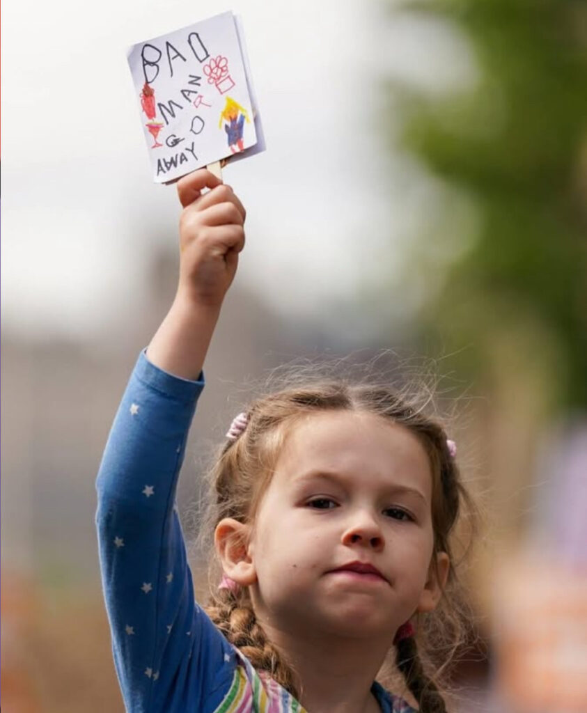 2025 07 Protest against Donald Trump in Scotland, photo of a determined lovely girl in braids wearing a colourful top with stars holding up her home made sign which says 'Bad Man Go Away'