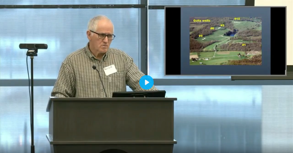 Photo of Ron Gulla presenting the 2025 keynote at Halt the Harm Network conference in Pittsburgh Pennsylvania, showing aerial of the frac wells on his farm