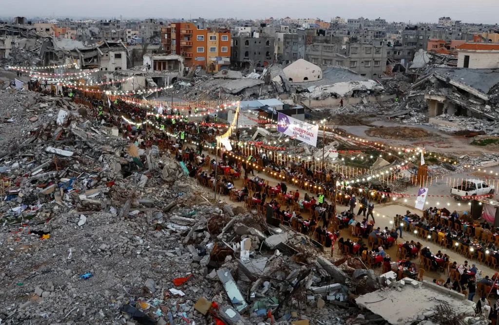 Rafah, Gaza: Palestinians break their fast by eating the iftar meals during the holy month of Ramadan, near the rubble of buildings Photograph: Hatem Khaled/Reuters in The Guardian