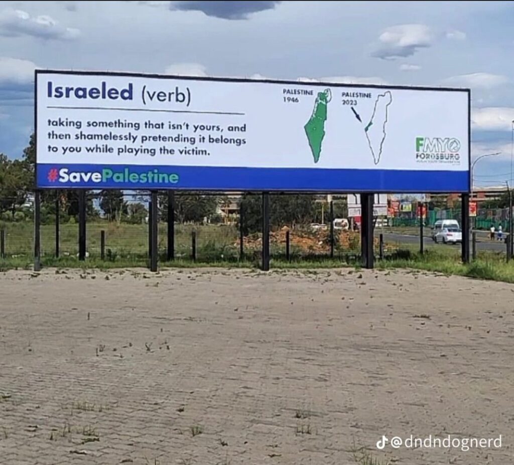 Photo of a billboard with map of Palestinian lands taken by Israel with text that reads: Israeled (verb) - taking something that isn't yours, and then shamlessly pretending it belongs to you while playing the victim